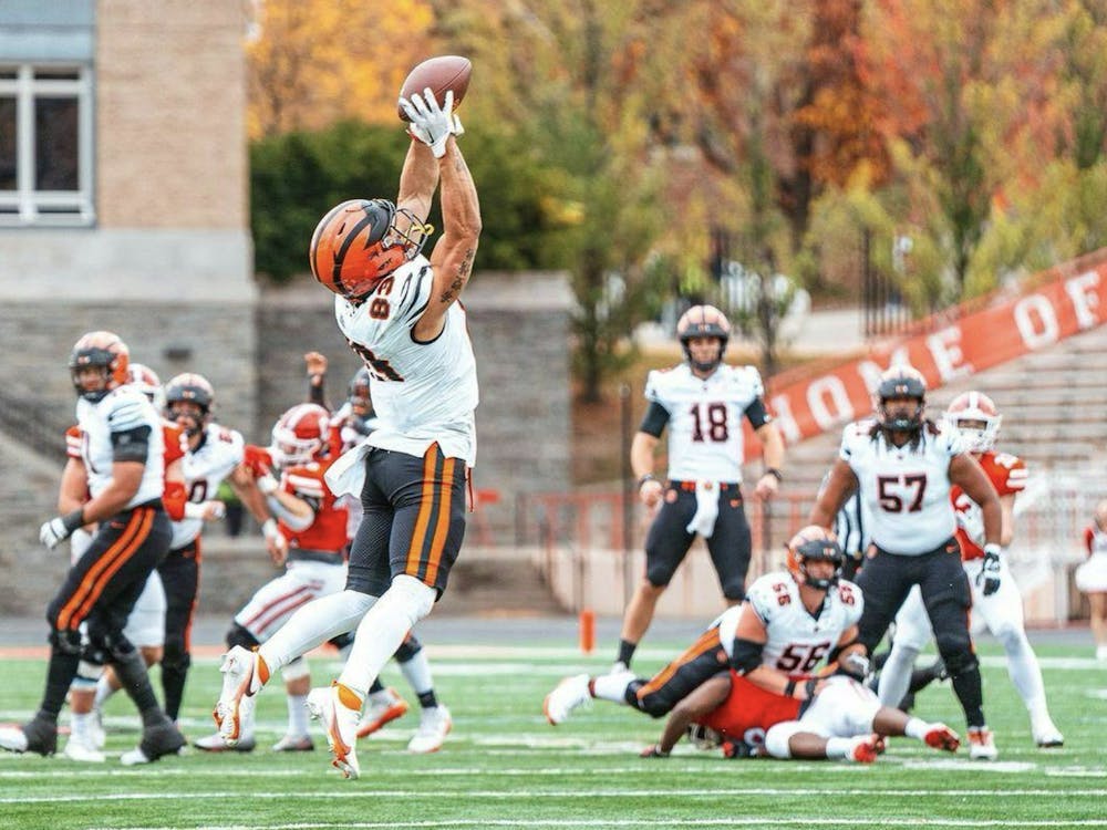 Football player catches ball with both hands overhead while in the air