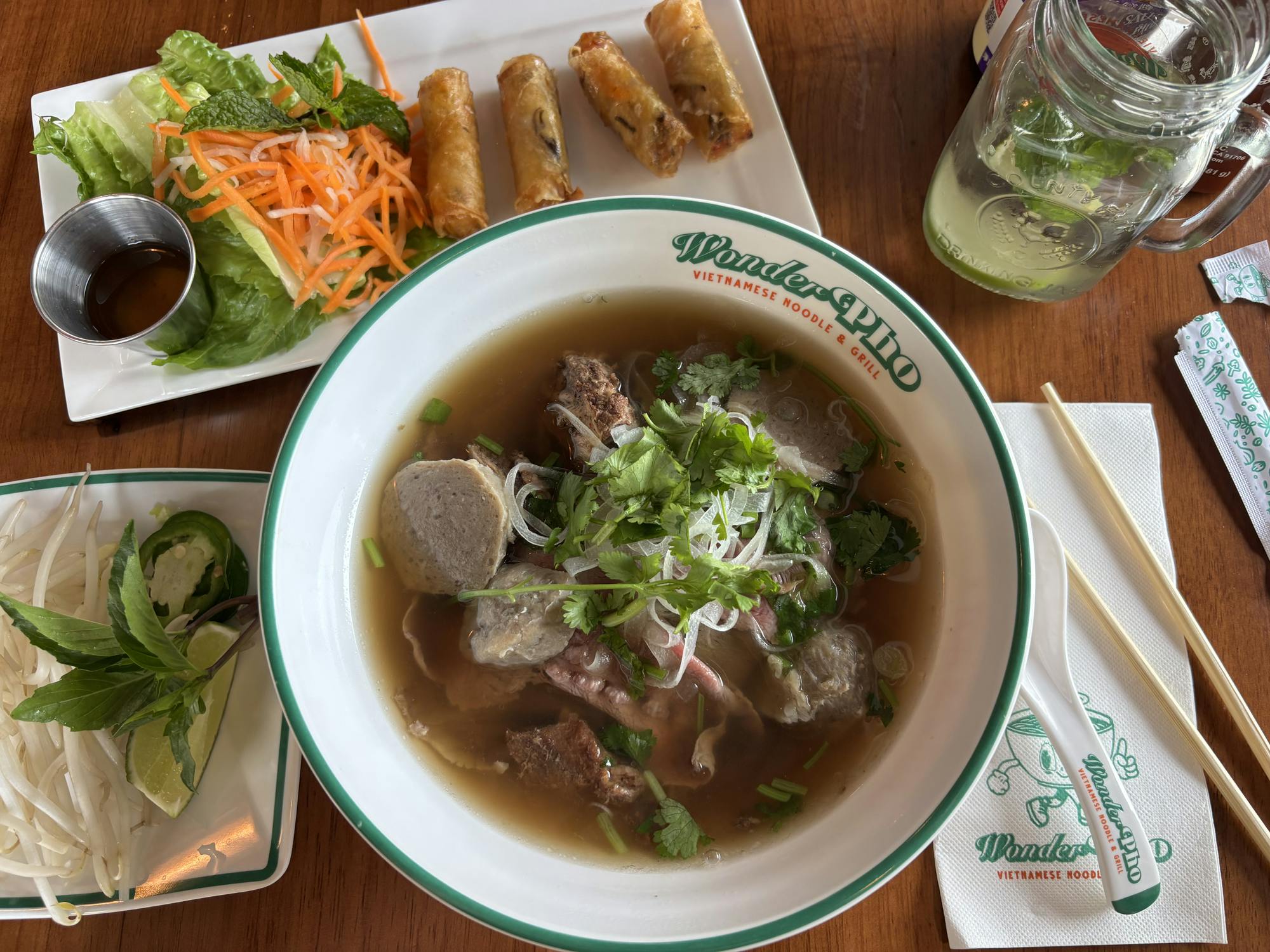 A variety of colorful dishes and drinks are on a brown table.