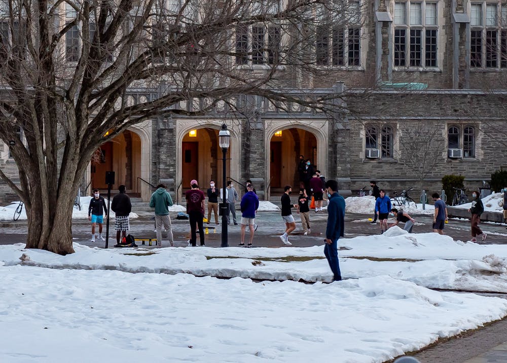 Photo of many students playing various outdoor games on a snow covered lawn in front of a brick building. 