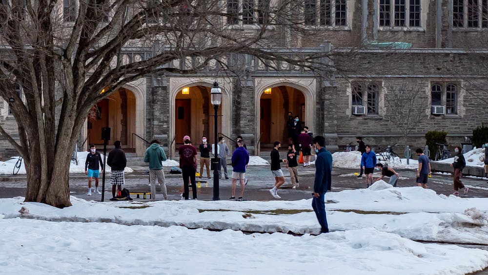 Photo of many students playing various outdoor games on a snow covered lawn in front of a brick building. 