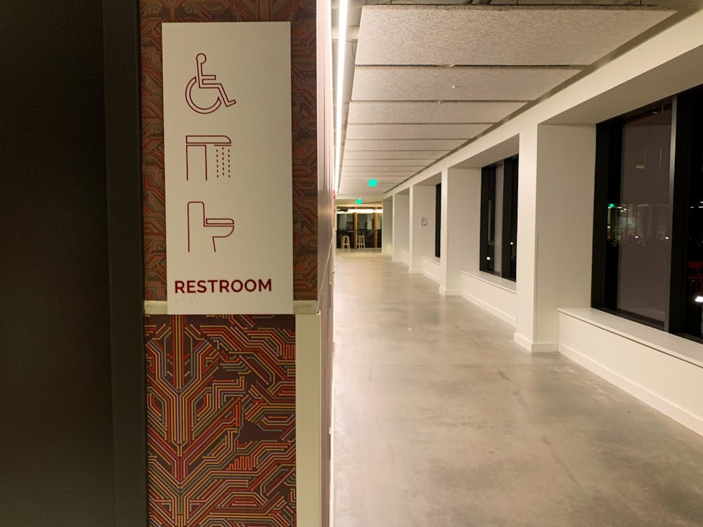 A hallway outside a gender-neutral bathroom with a sign for the bathroom. 