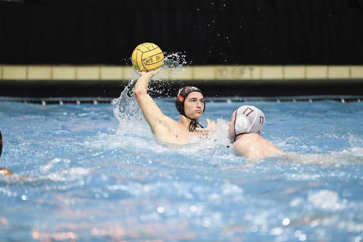 Senior attacker and captain Pierce Maloney cocks his right arm back in preparation for a shot on goal as he's defended by a Harvard Crimson defender.