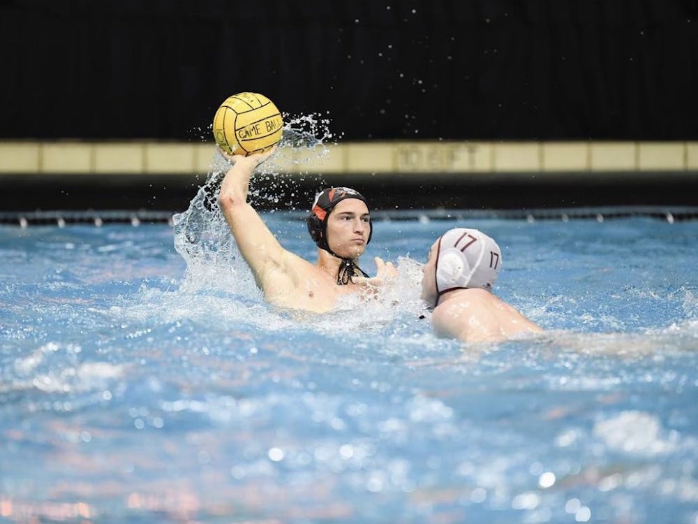 Senior attacker and captain Pierce Maloney cocks his right arm back in preparation for a shot on goal as he's defended by a Harvard Crimson defender.