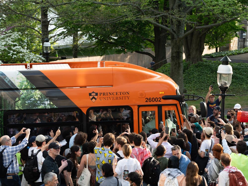 Crowd of people around an orange bus.