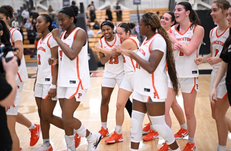 Players in white jerseys walk across a basketball floor.