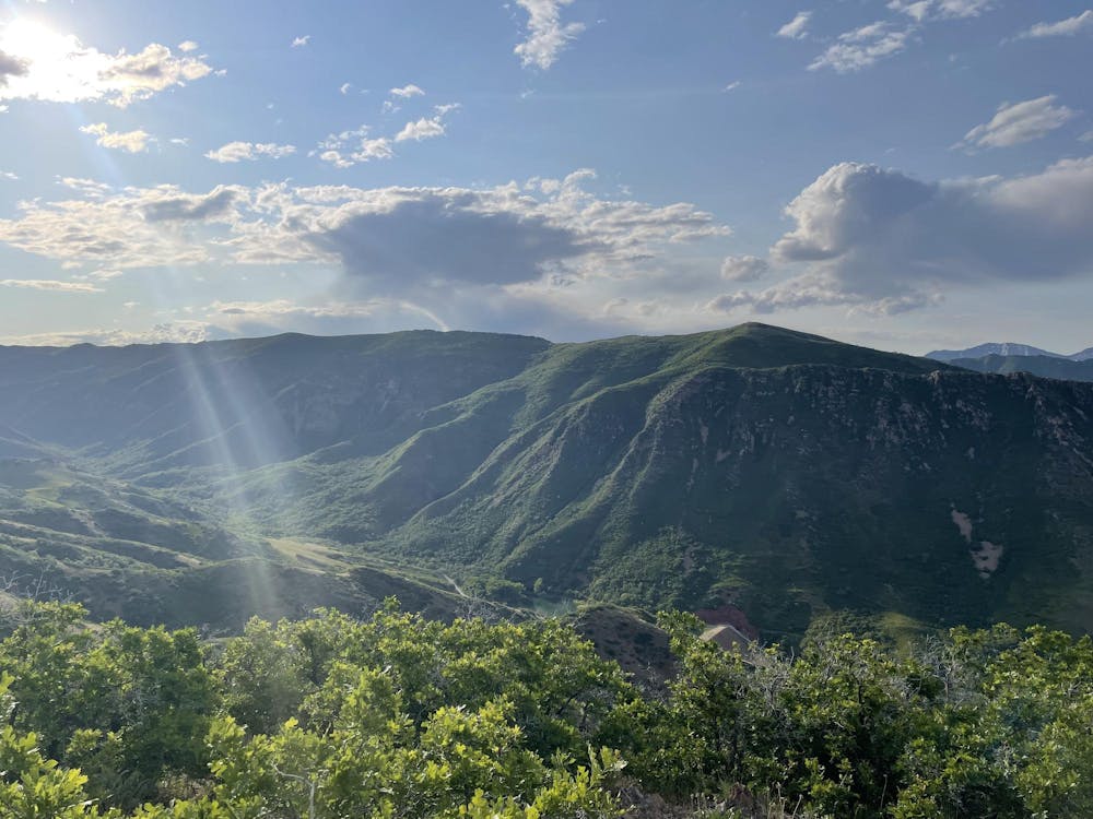 An expansive view of a green mountainscape and blue sky with white clouds.