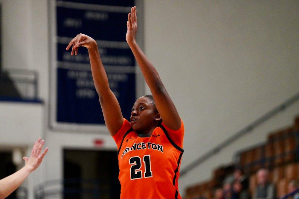 A player in an orange jersey shooting a basketball and jumping.