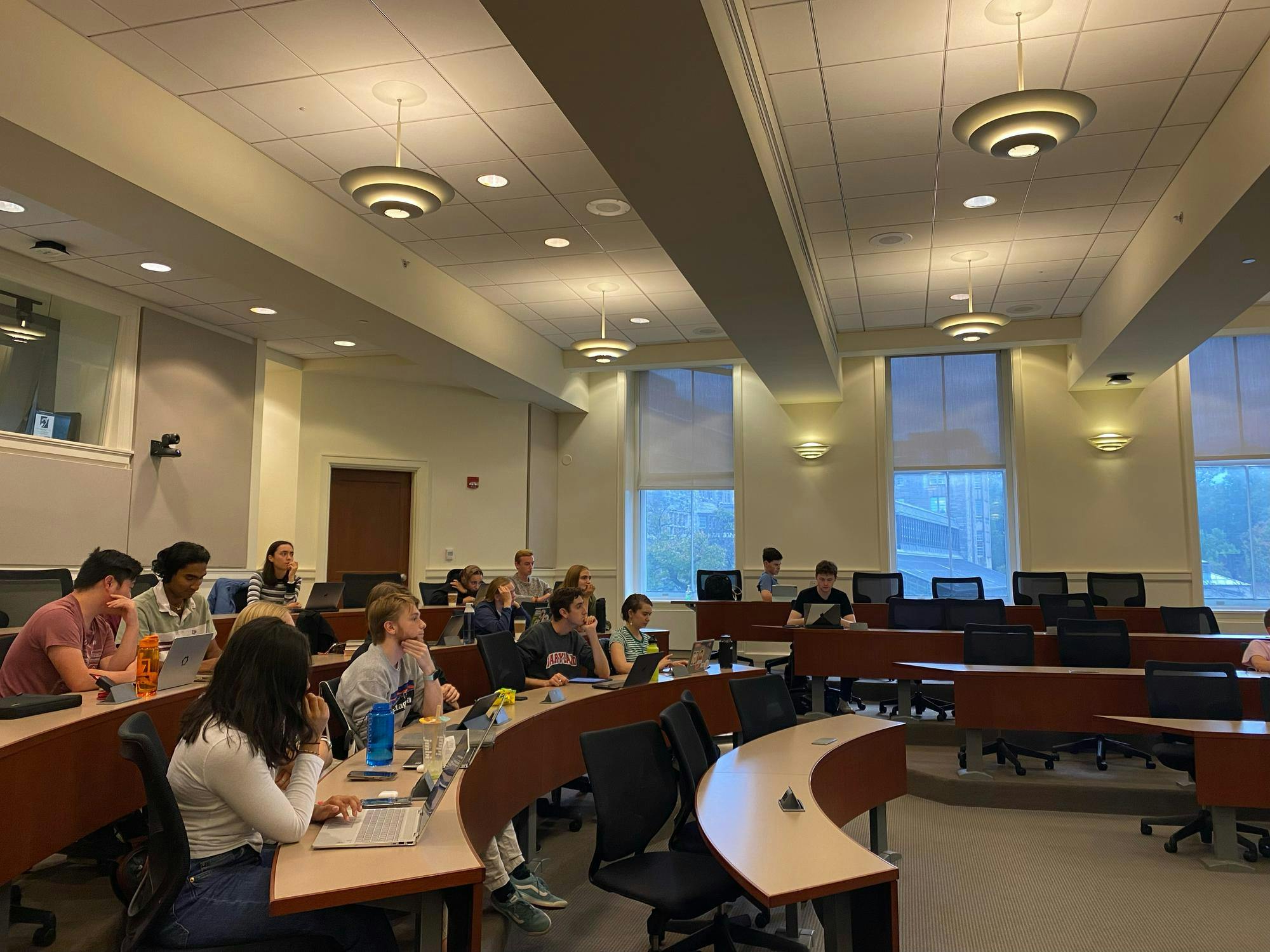 A dozen students sit in a lecture hall. 