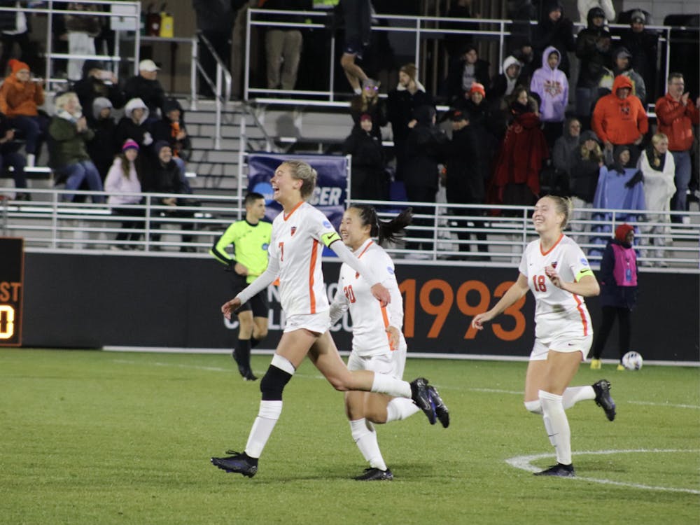 three soccer players run while smiling with arms raised slightly at sides