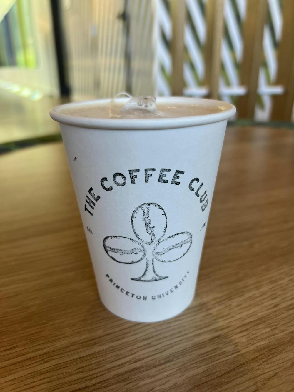A close-up photo of a coffee cup with the words "The Coffee Cup" and coffee beans printed on the side of the cup.
