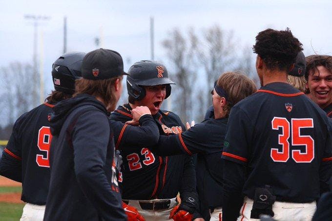 Group of players in orange and black celebrating with player in middle yelling. 