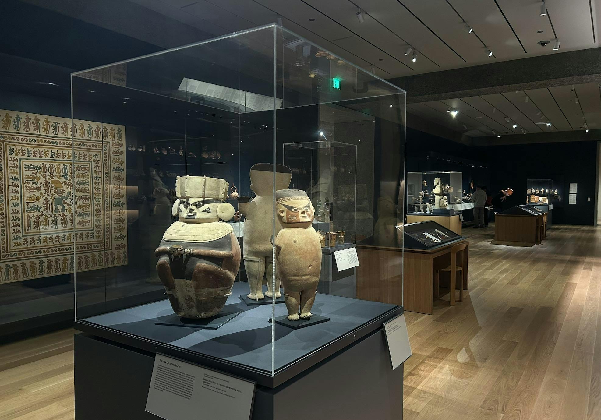 An image with a display of three ceramic figurines in the foreground with the rest of the gallery in the background. 