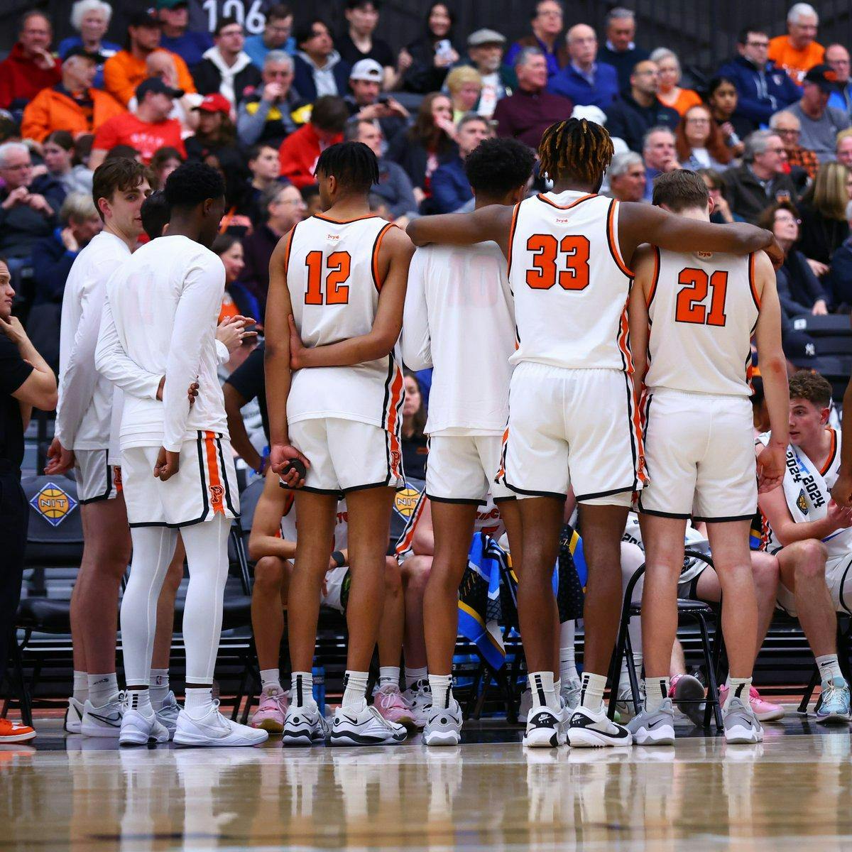 Seven men in white jerseys face away from camera towards their team.