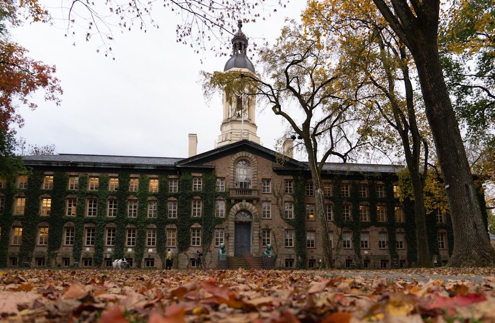 Nassau Hall, a large Renaissance-style building with ivy on the walls and a bell tower on top, surrounded by fall leaves. 