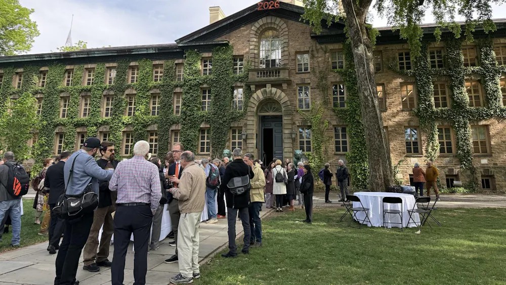 Faculty gather outside a building.