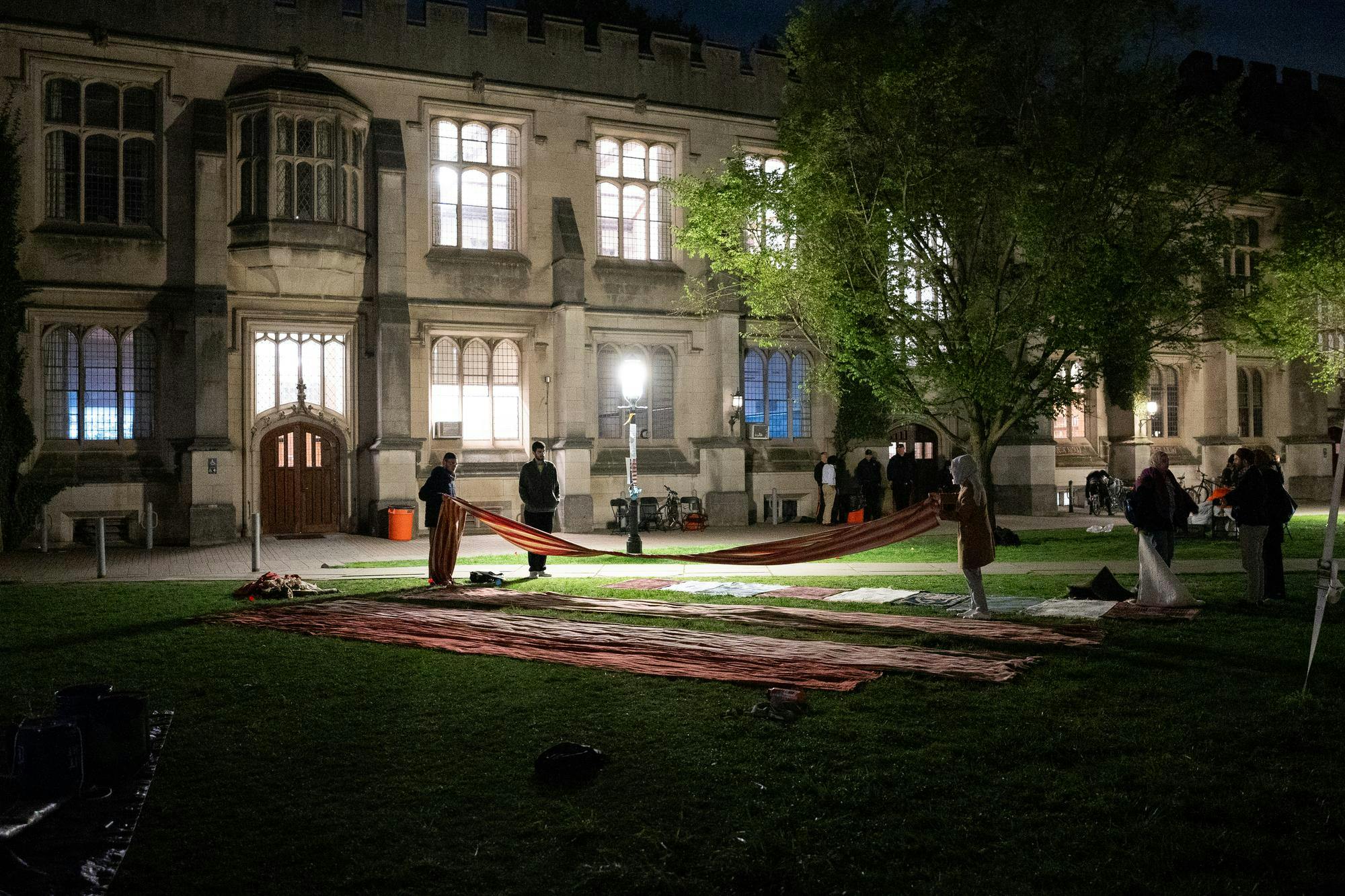 Two women hold the ends of a long piece of cloth at night