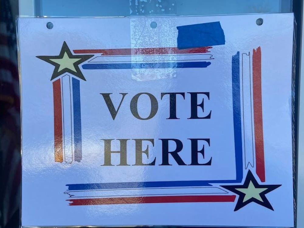 A colorful sign that says "vote here" in all capital letters.