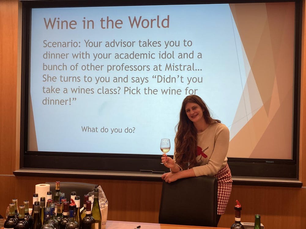 Miller stands behind a desk with several bottles of wine that participants sampled during her Wintersession workshop.