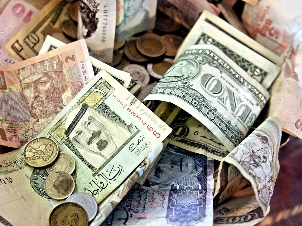 Various bills and coins of different denominations and currencies filling the picture, including some one and ten US dollar bills.