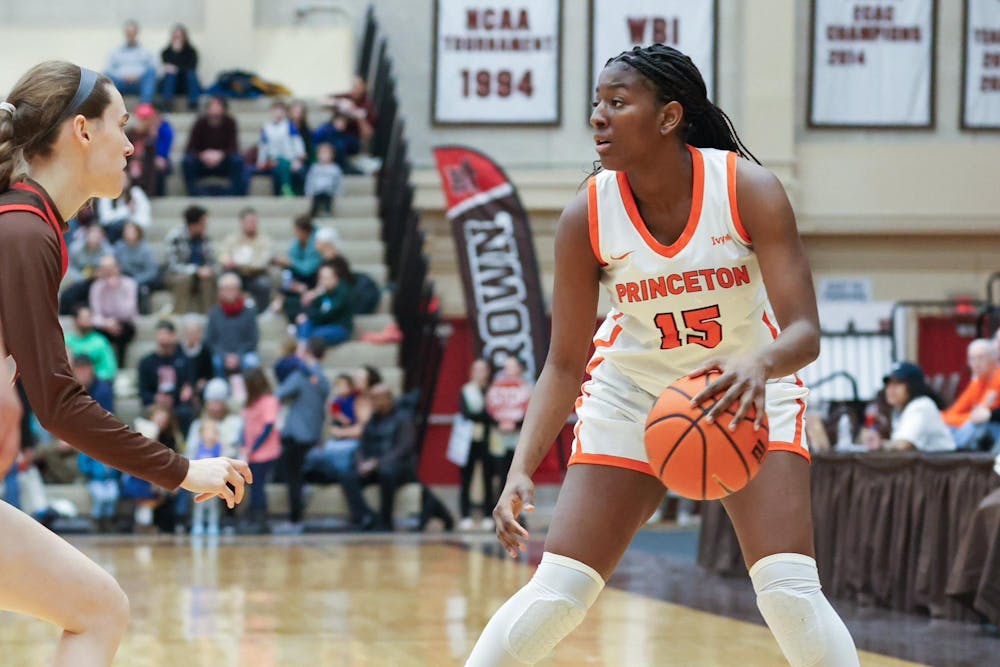 A woman wearing a white jersey dribbling a basketball on the court. 