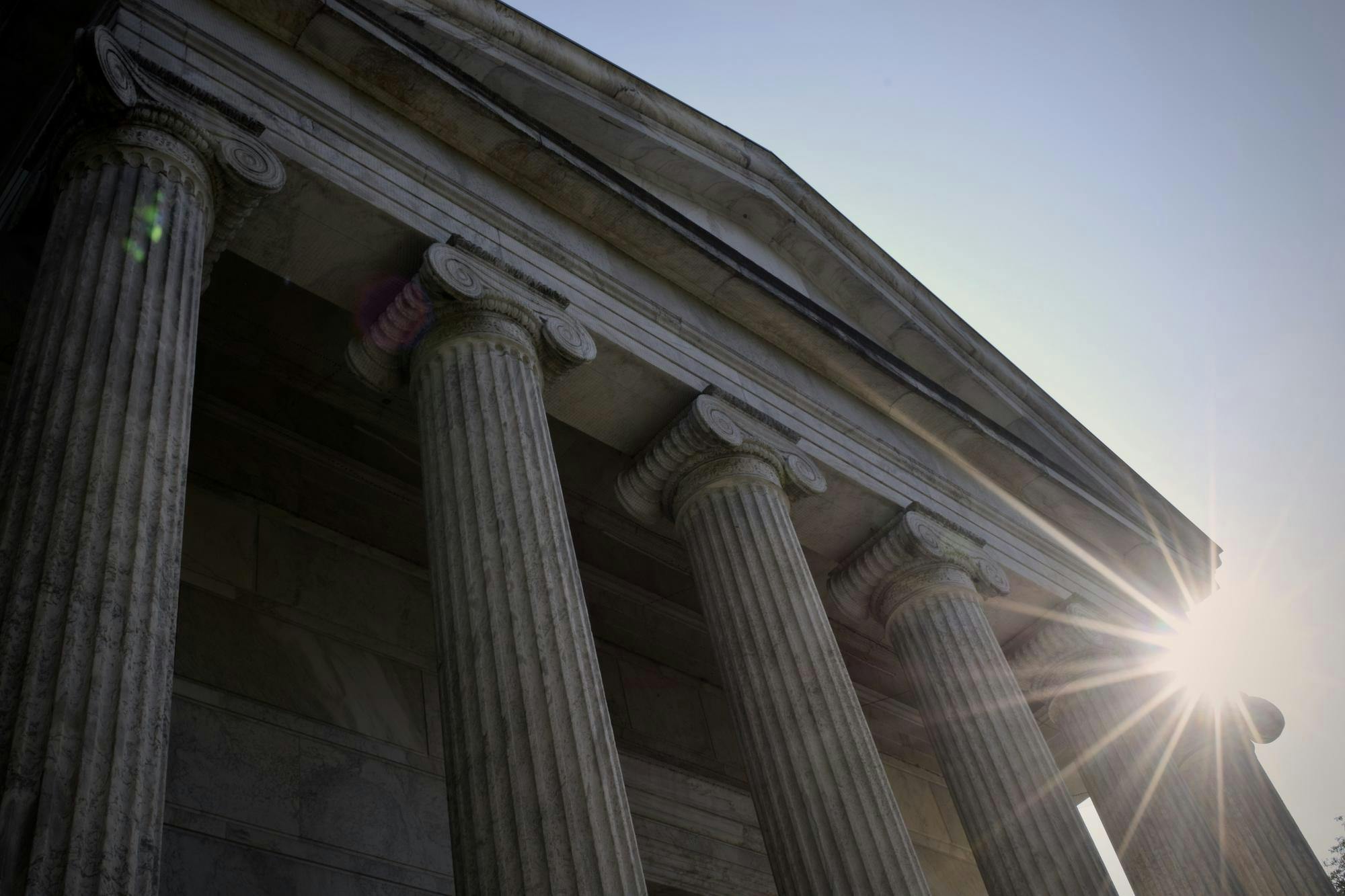 A large white building with pillars, photographed from the ground. 