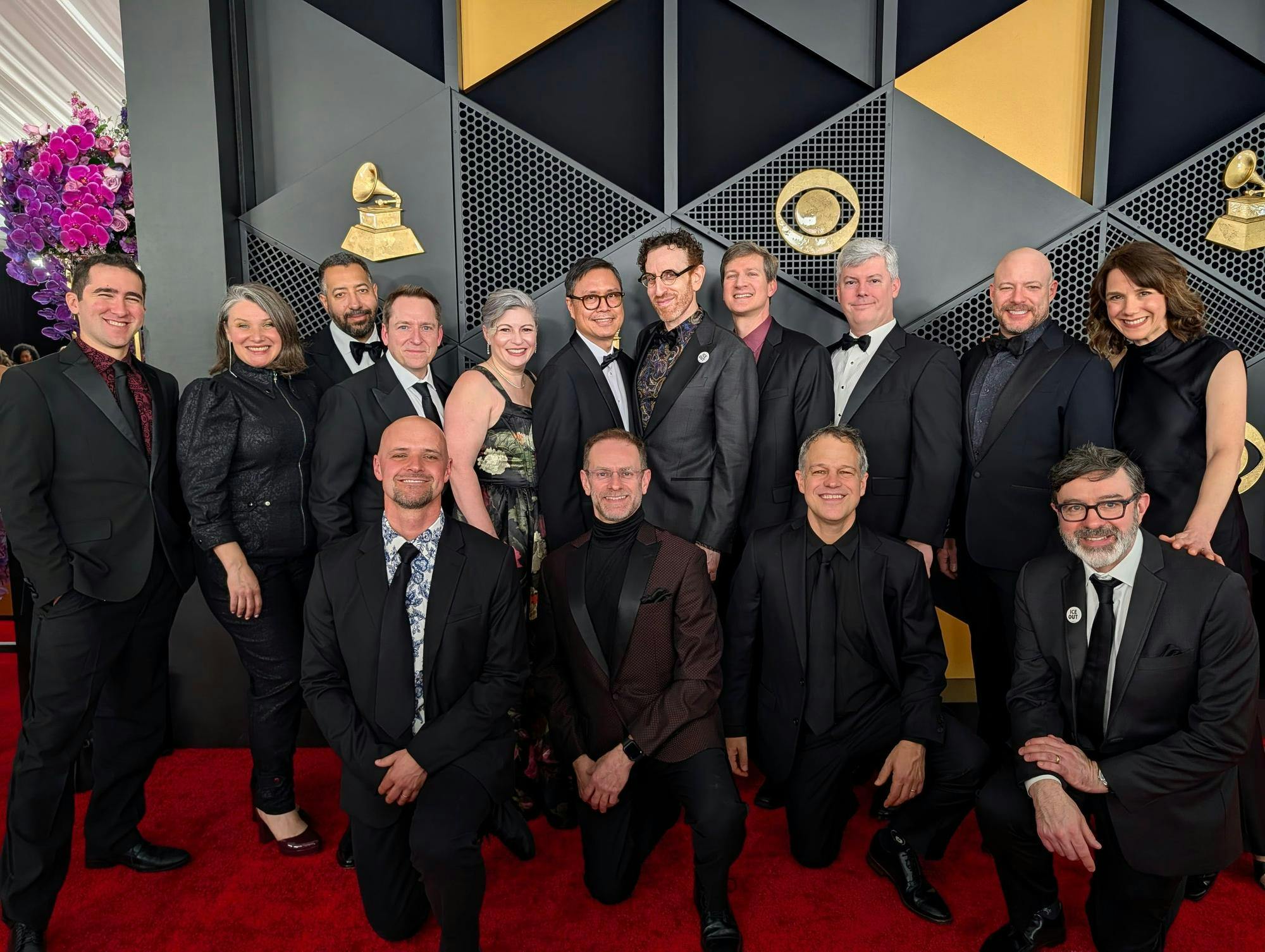Men and women in elegant attire on a red carpet.