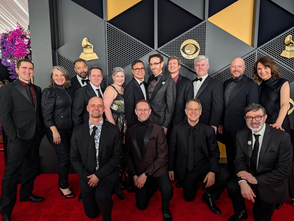 Men and women in elegant attire on a red carpet.
