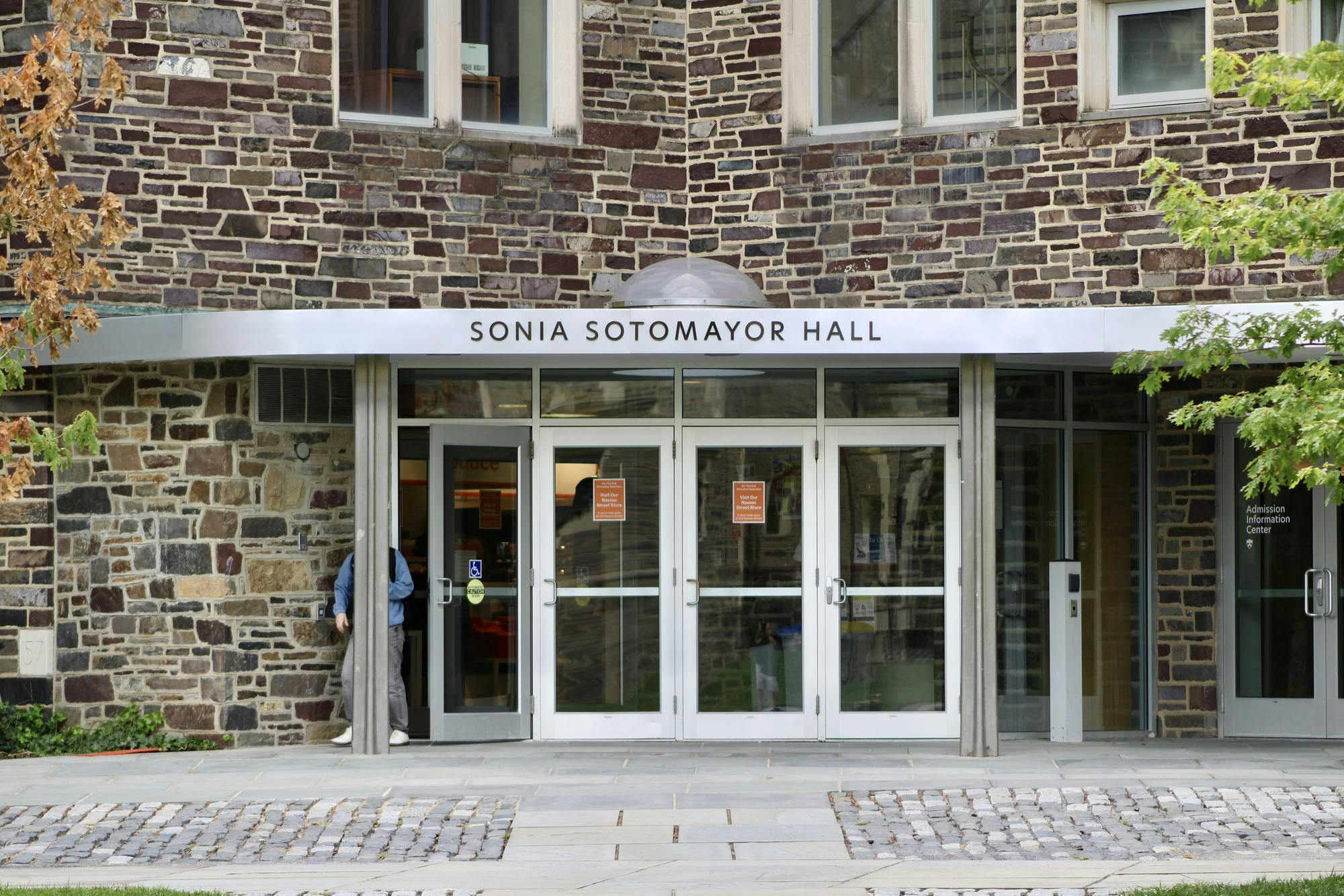 A stone building with four glass doors, one of which is ajar