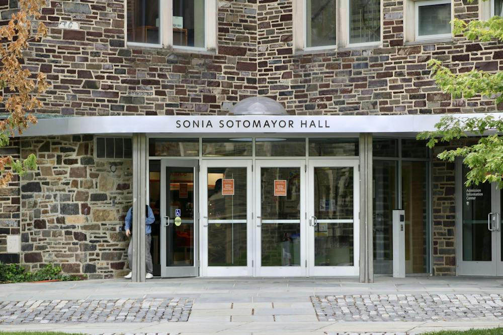 A stone building with four glass doors, one of which is ajar