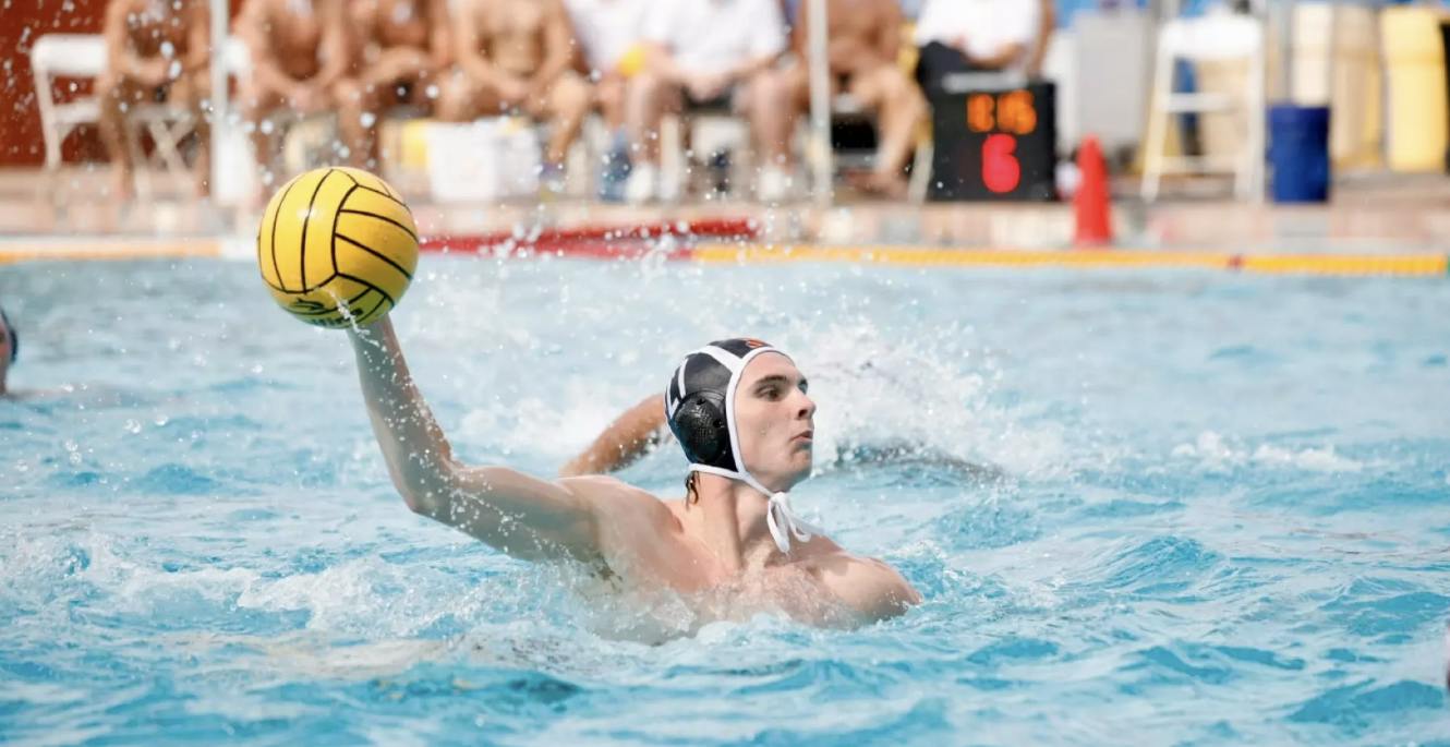 A men’s water polo player aiming the ball.