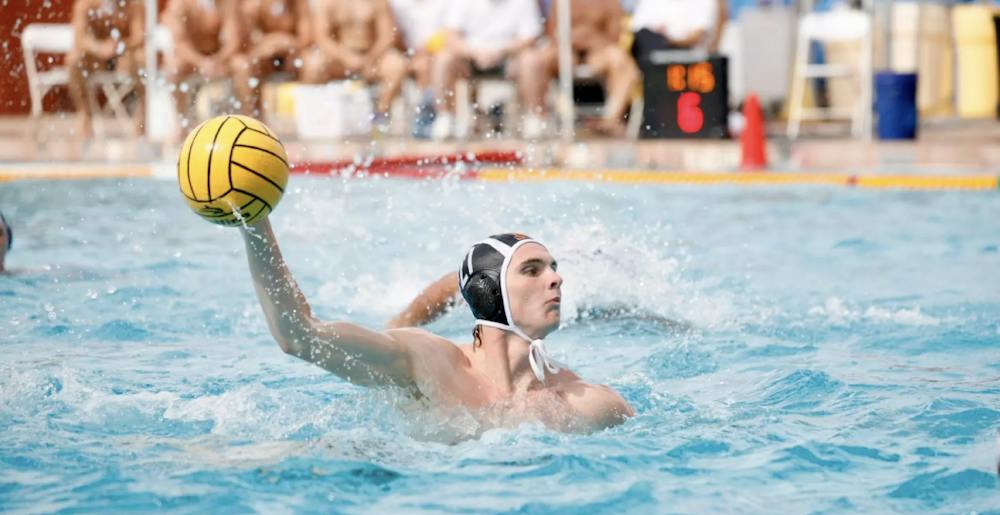 A men’s water polo player aiming the ball.