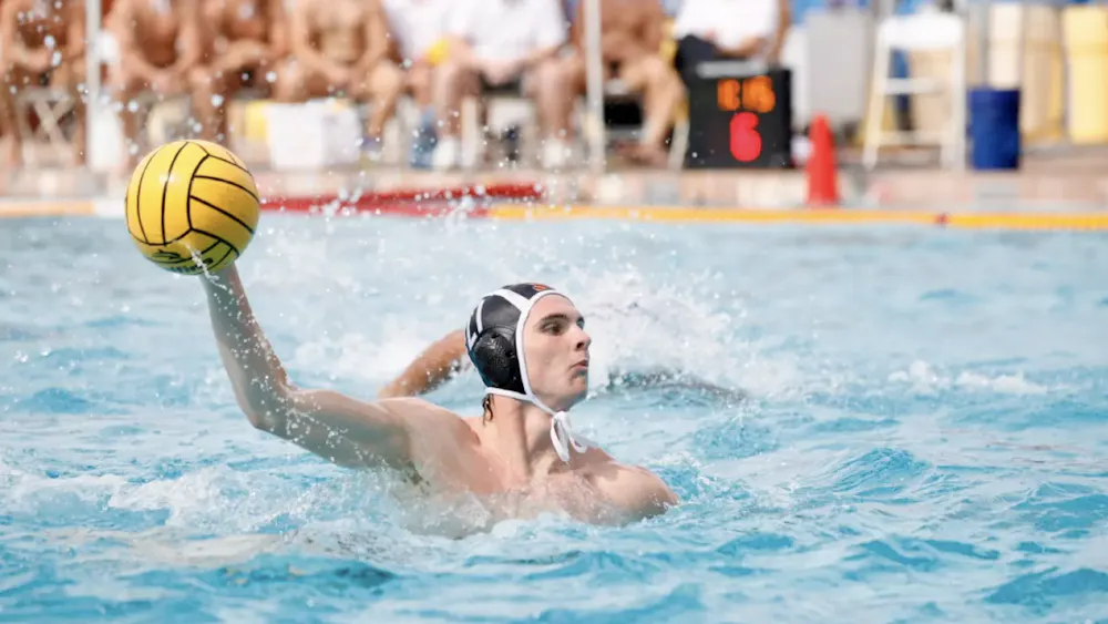 A men’s water polo player aiming the ball.