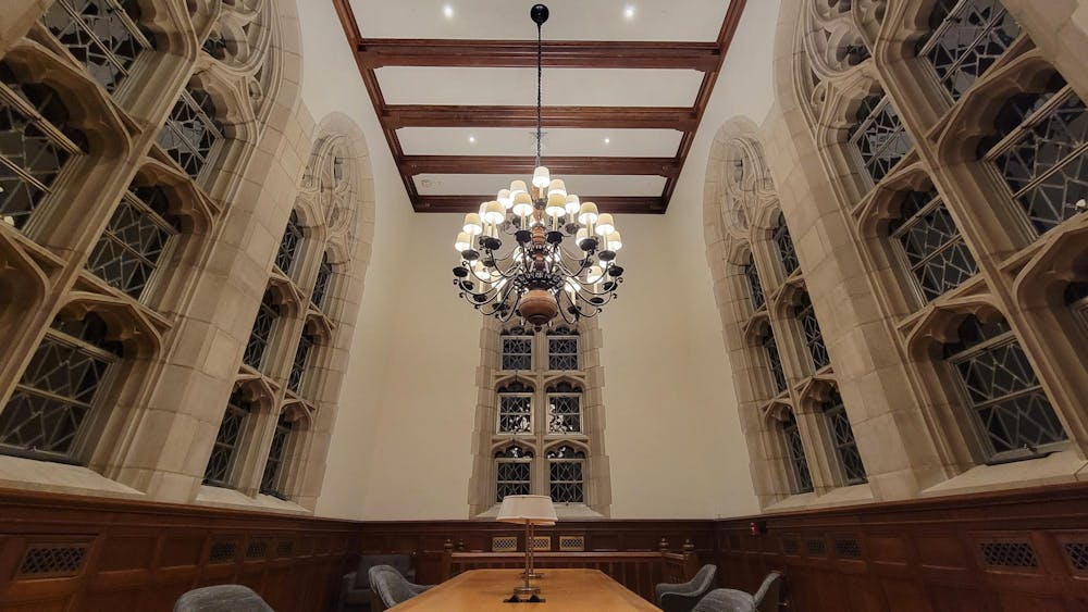 Photo of lit chandelier over wooden table in Firestone Tower at night