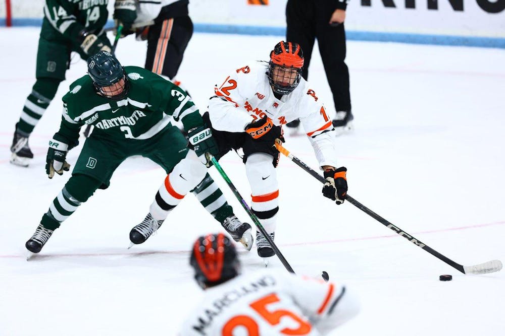 A hockey player skating on ice with possession of the puck, keeping it away from an opposing player.