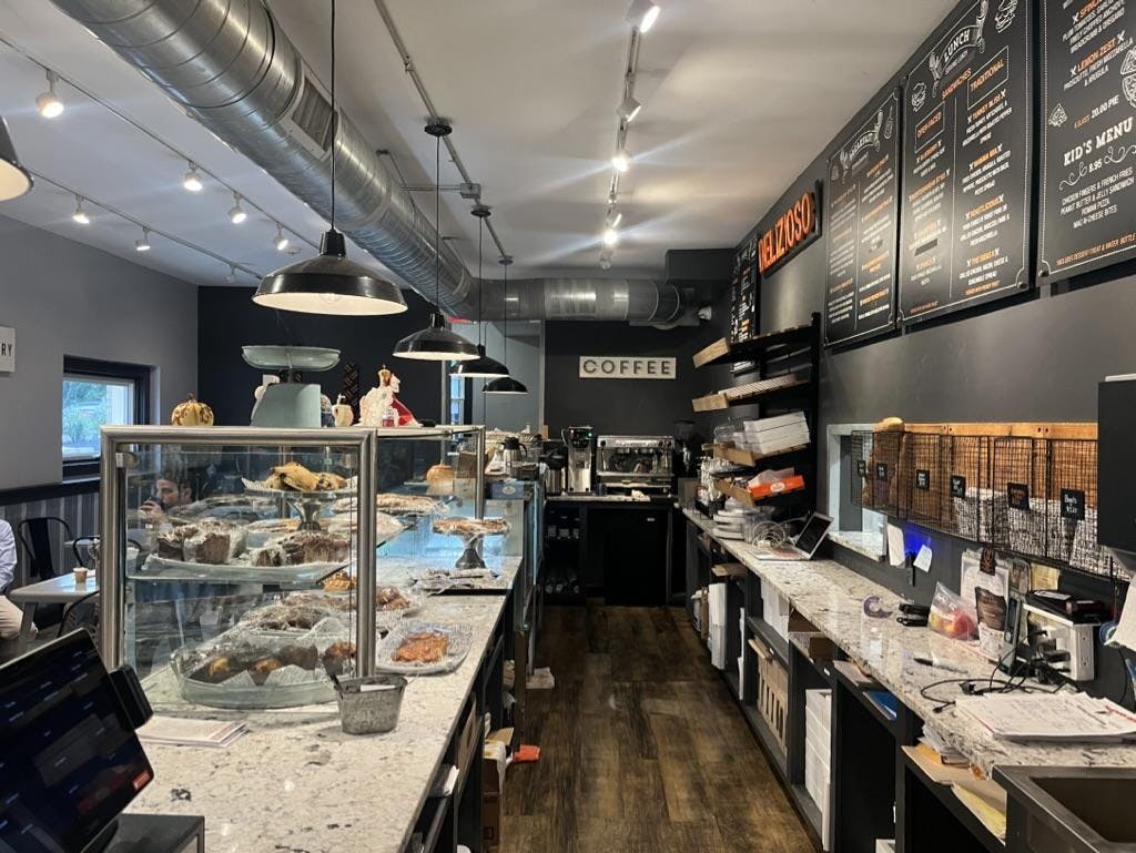 Display case of baked goods, coffee machines, and packaging set-up.