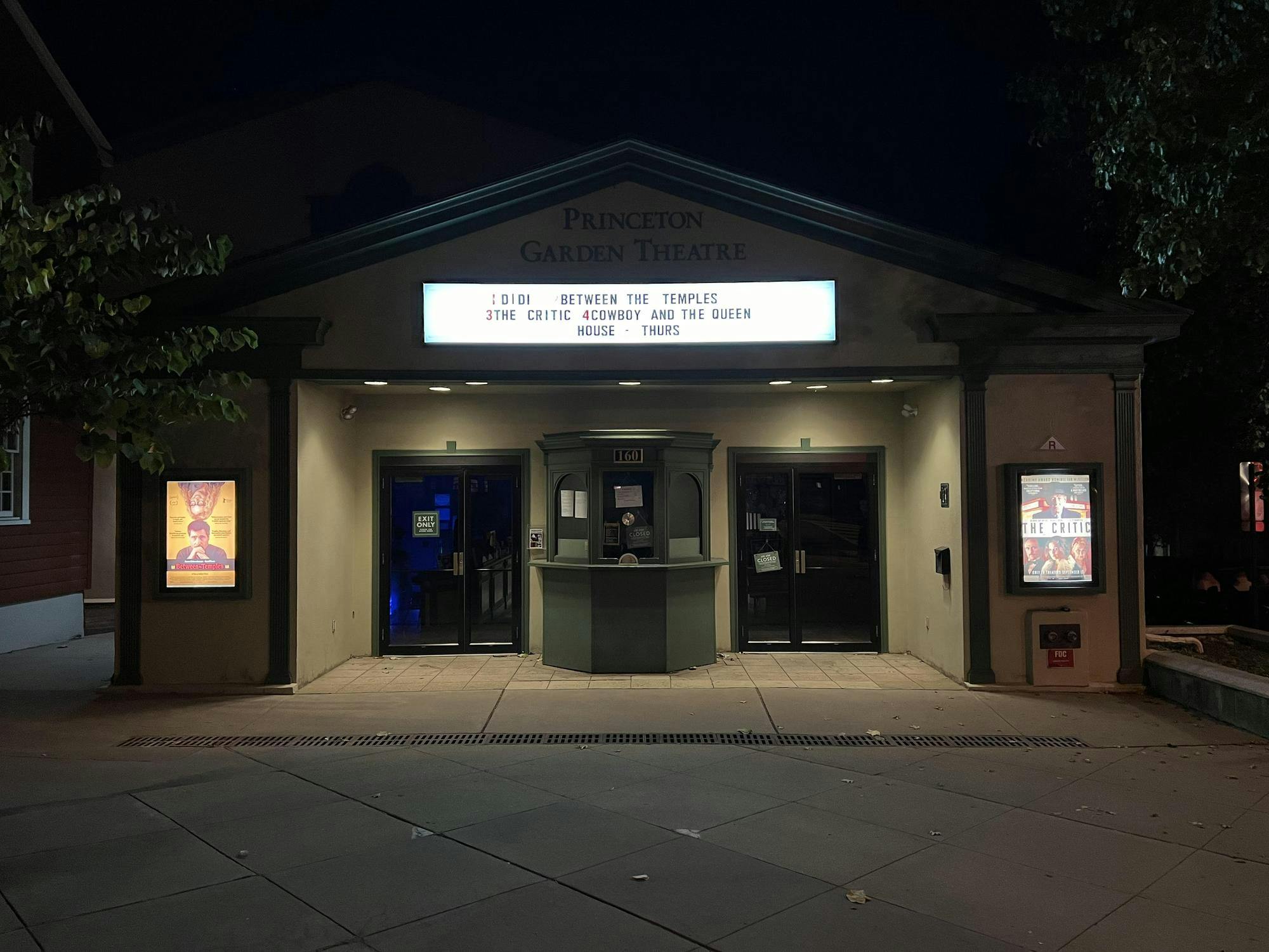 Movie theater at night with a glowing sign showing the black text.