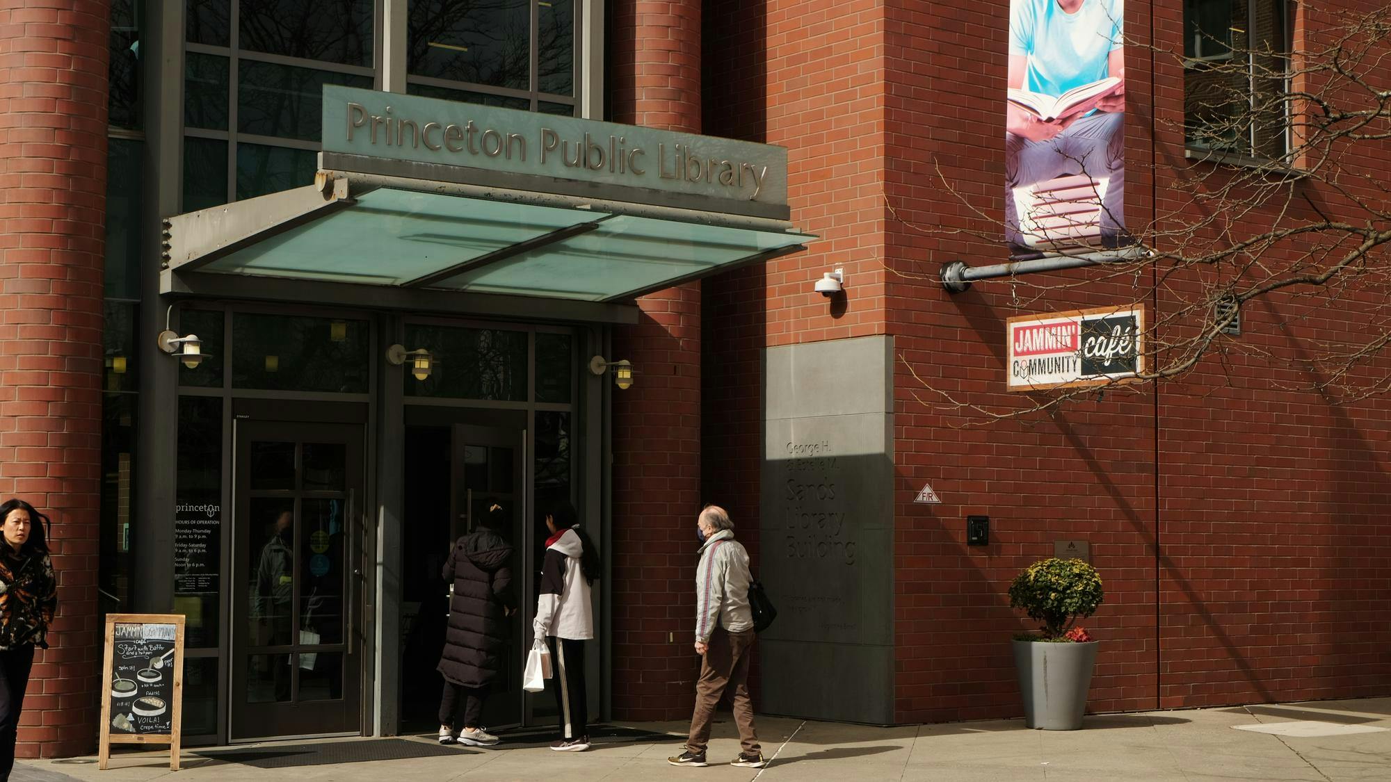 A brick building with large glass doors, the Princeton Public Library sign above, and a café sign on the side.