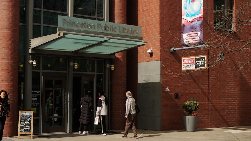 A brick building with large glass doors, the Princeton Public Library sign above, and a café sign on the side.