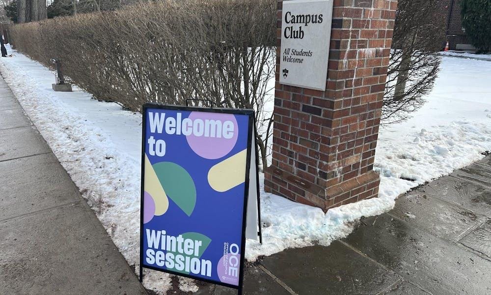 A sign that says “Welcome to Wintersession” in front of a snowy pillar and bush
