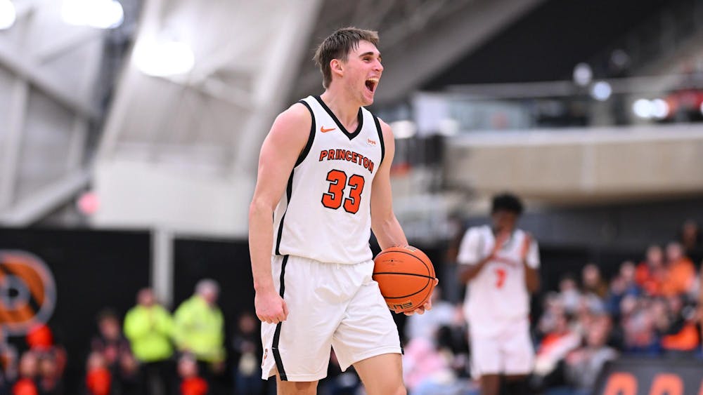A player in a white jersey yells in excitement while holding a basketball.