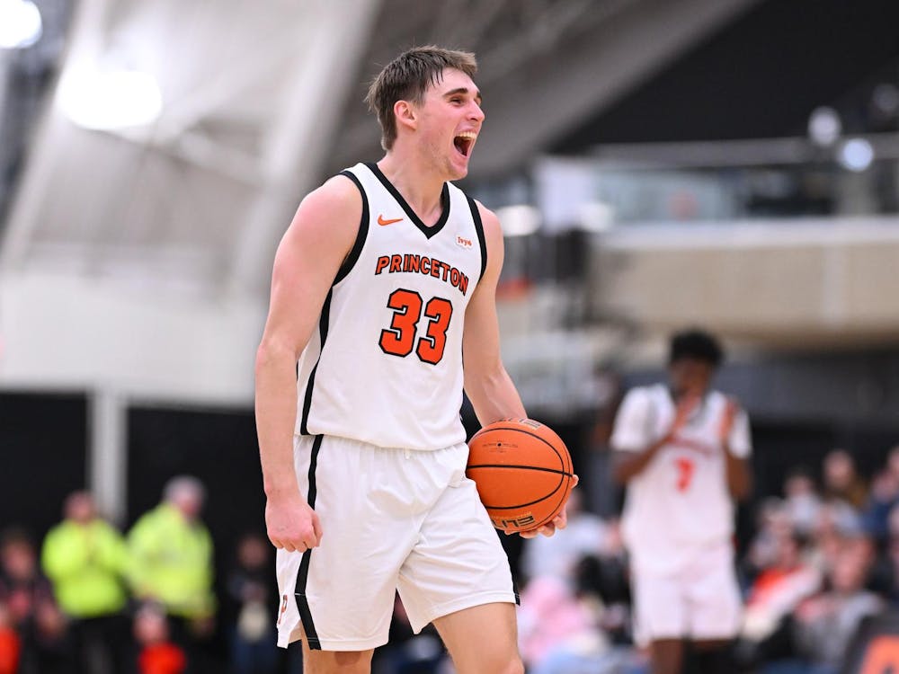 A player in a white jersey yells in excitement while holding a basketball.