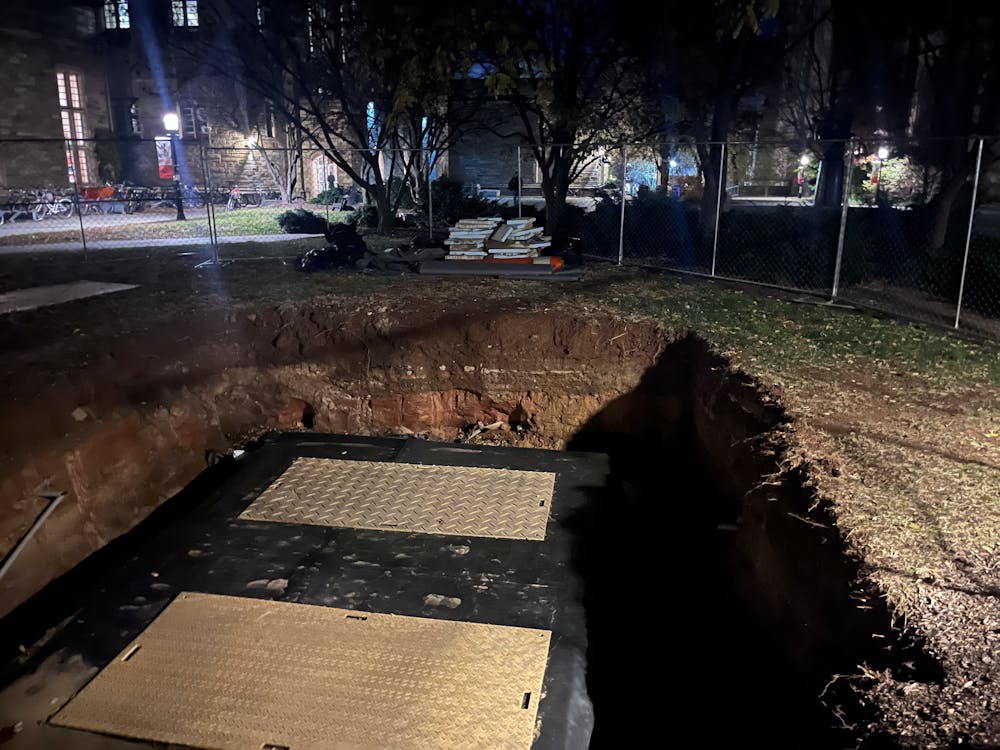 Spot of earth with a hole in it, surrounded by fencing, at night.