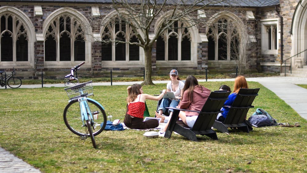 A group of people sits in circle on grass.