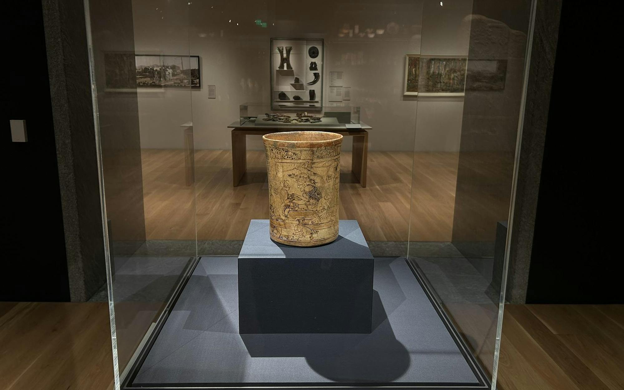 An image of a vase inscribed with images encased in a display. 