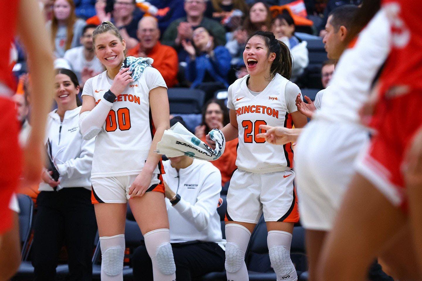 Girls in white basketball uniforms smiling and celebrating during the middle of a game. 