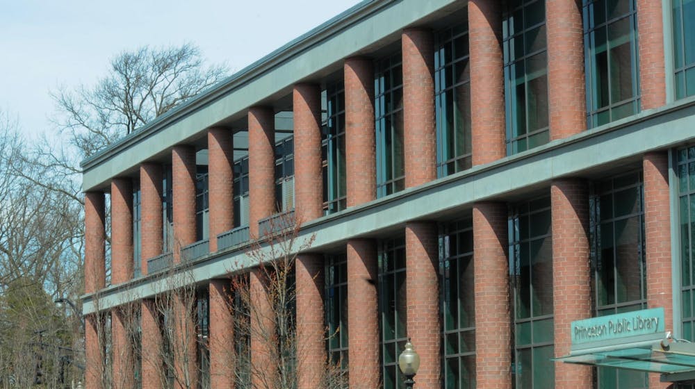 A large glass building with brick pillars stands in front of a blue sky.