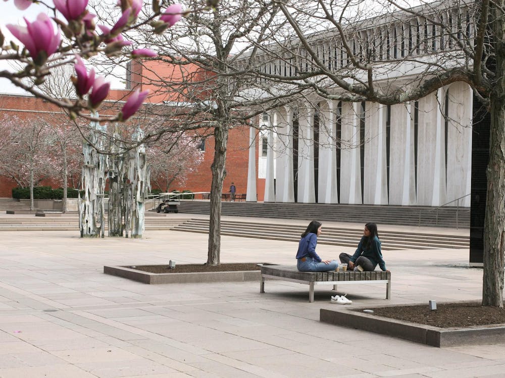 Two students talking on a bench outside the SPIA building in springtime.
