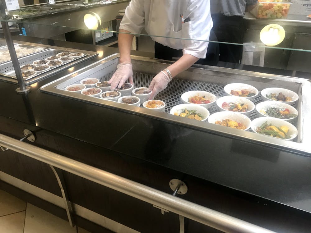 <p>A staff member in the Rocky Mathey dining hall places plastic wrap over individual servings. Due to the coronavirus outbreak, food is no longer self-serve.&nbsp;</p>
<h6>Photo Credit: Claire Silberman / The Daily Princetonian</h6>