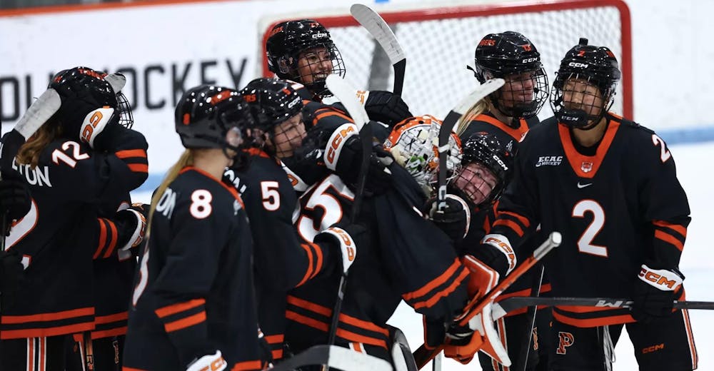 An ice hockey team celebrates a win in a huddle on the ice.