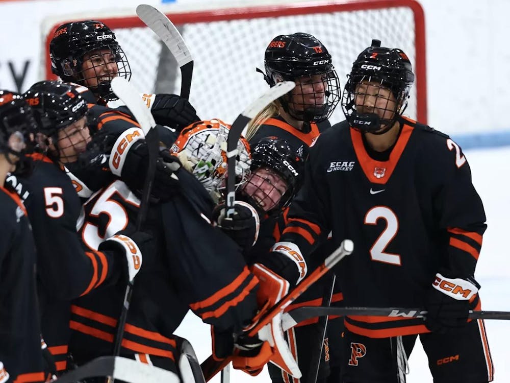 An ice hockey team celebrates a win in a huddle on the ice.